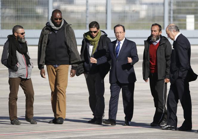Les quatre derniers otages, Marc Féret, Thierry Dol, Pierre Legrand et Daniel Larribe, accompagnés de François Hollande et de Laurent Fabius, le 30 octobre 2013, à l’aéroport de Villacoublay (Yvelines). KENZO TRIBOUILLARD / AFP
