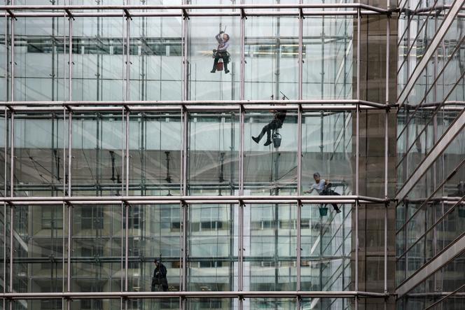 Des nettoyeurs de vitres, sur un immeuble du quartier d’affaires de la Défense (Hauts-de-Seine), le 9 octobre 2025. LUDOVIC MARIN/AFP
